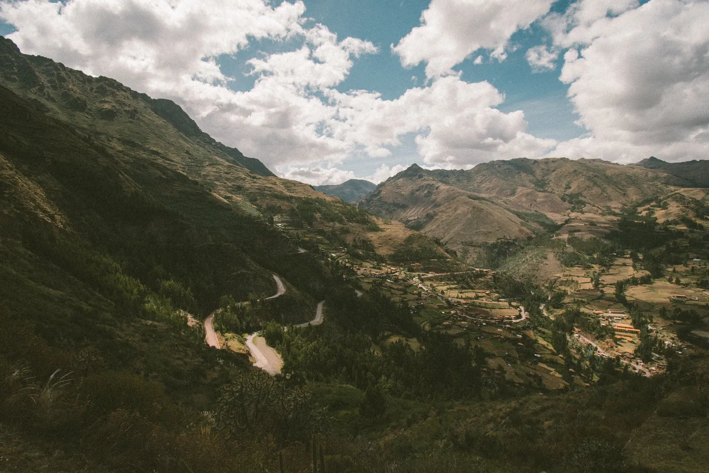 Valle verde y campos en Cusco, Perú, con construcciones dispersas.